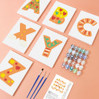 Colorful letter cards with paintbrushes and markers on a pink background
