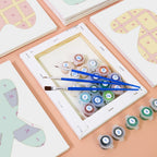 Set of paintbrushes and color swatches on a table with a digital device displaying a grid.