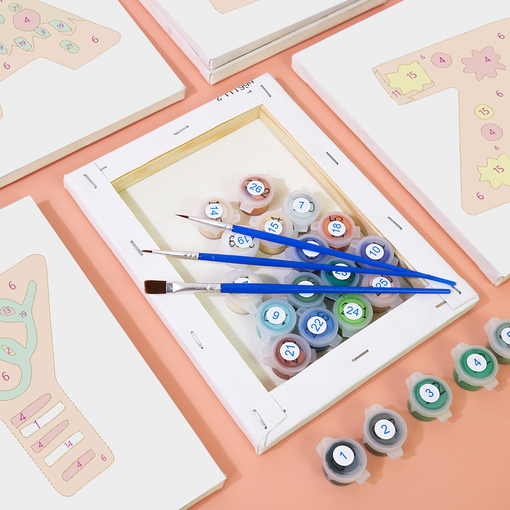Artistic setup with paint tubes and brushes on a digital device screen, surrounded by stationery items.