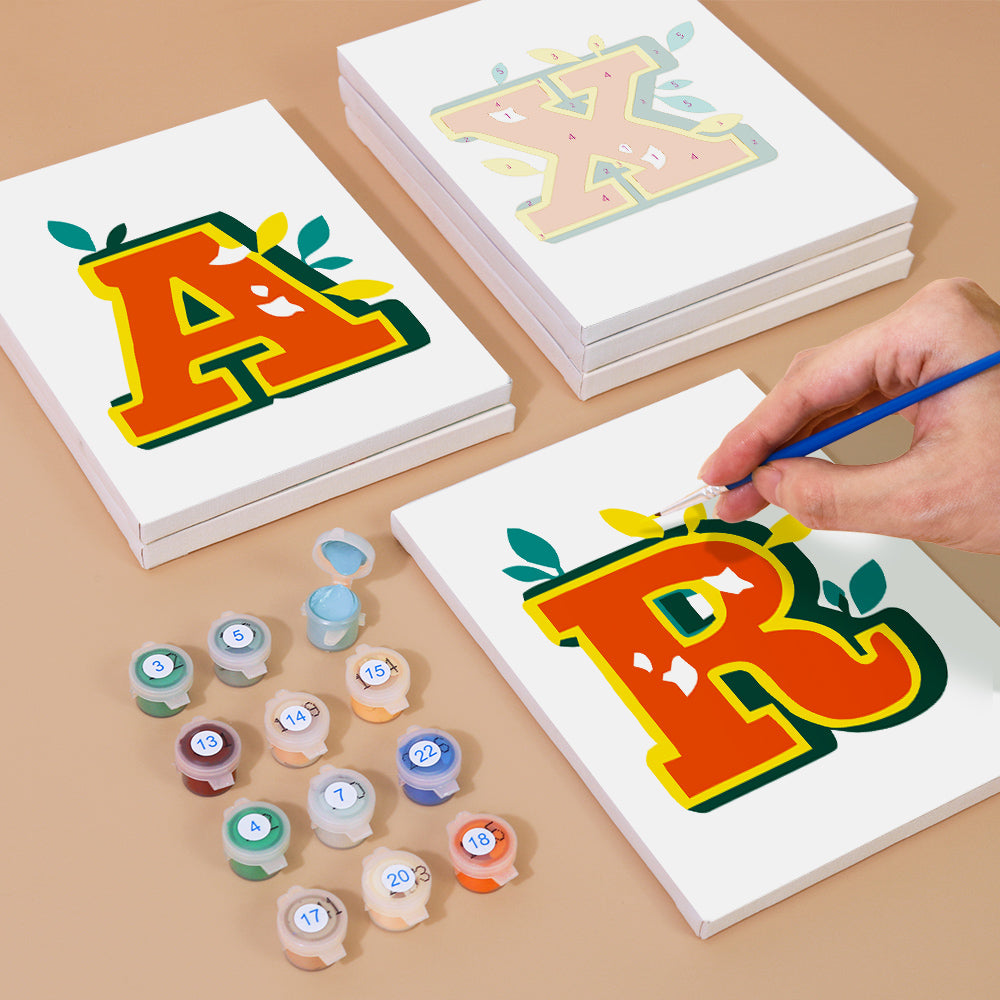 Children's art project with painted letters 'A' and 'R' on white paper, surrounded by paint containers.