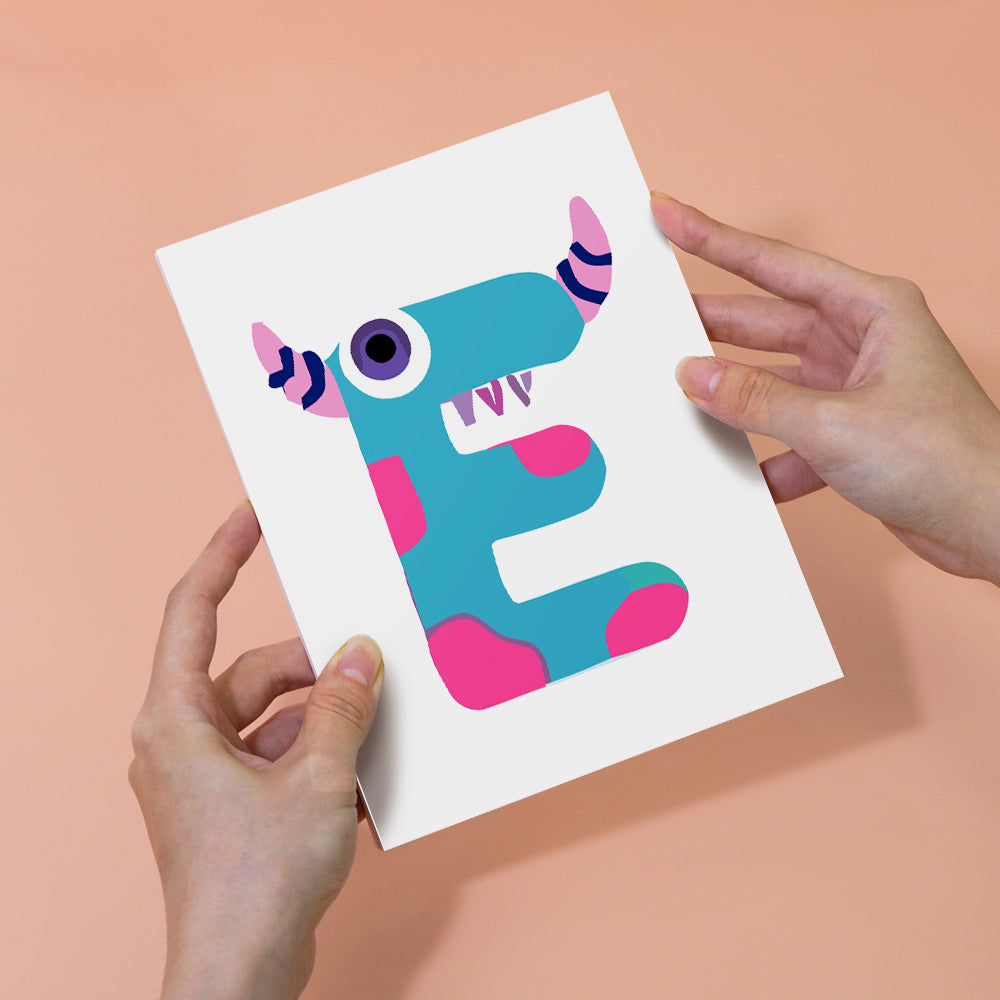 Card with a colorful letter 'E' design held by hands against a peach background