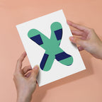Hands holding a card with a green and blue abstract design on a peach background