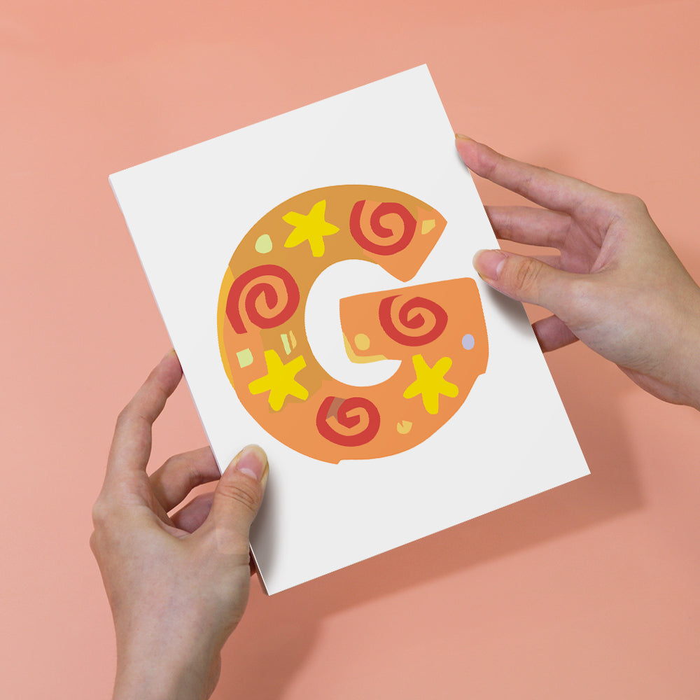 Letter 'G' design on a card held by hands against a pink background