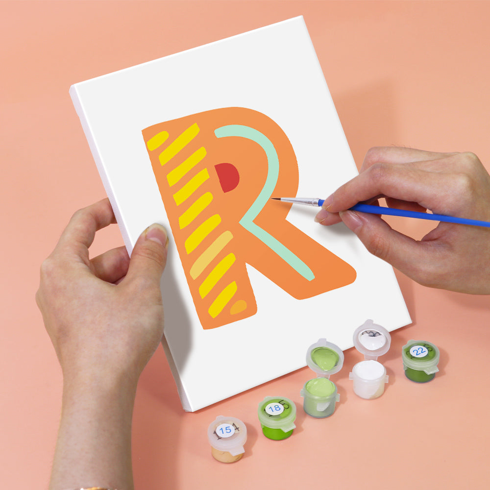 Person painting a colorful letter 'R' on a white board with paint containers below.