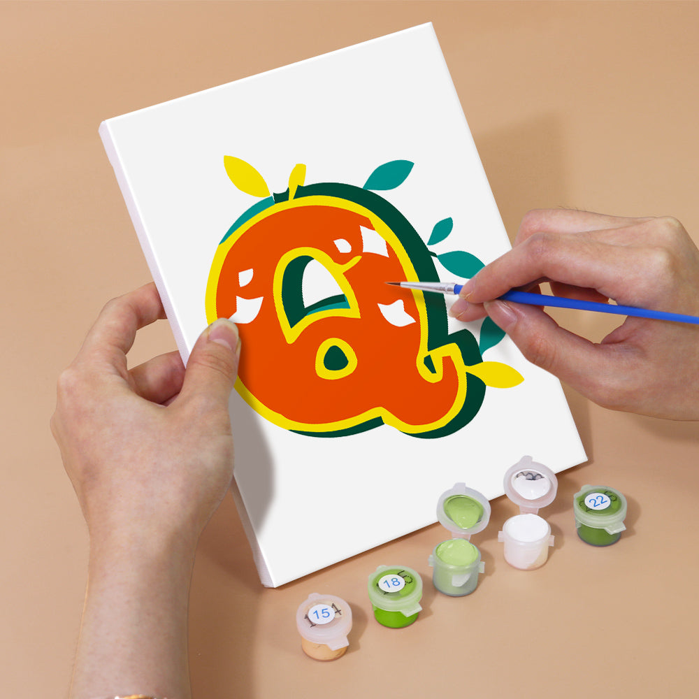 Person painting a colorful letter 'Q' on a white canvas with paint supplies on a beige surface.