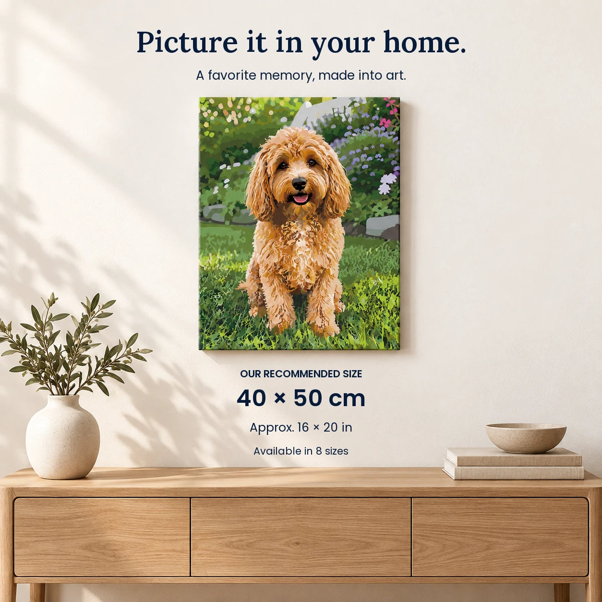 A vertical canvas wall art print showing a fluffy golden-brown dog sitting in a green garden, displayed on a light beige wall above a wooden console table with a vase and books. Text on the image reads 'Picture it in your home.