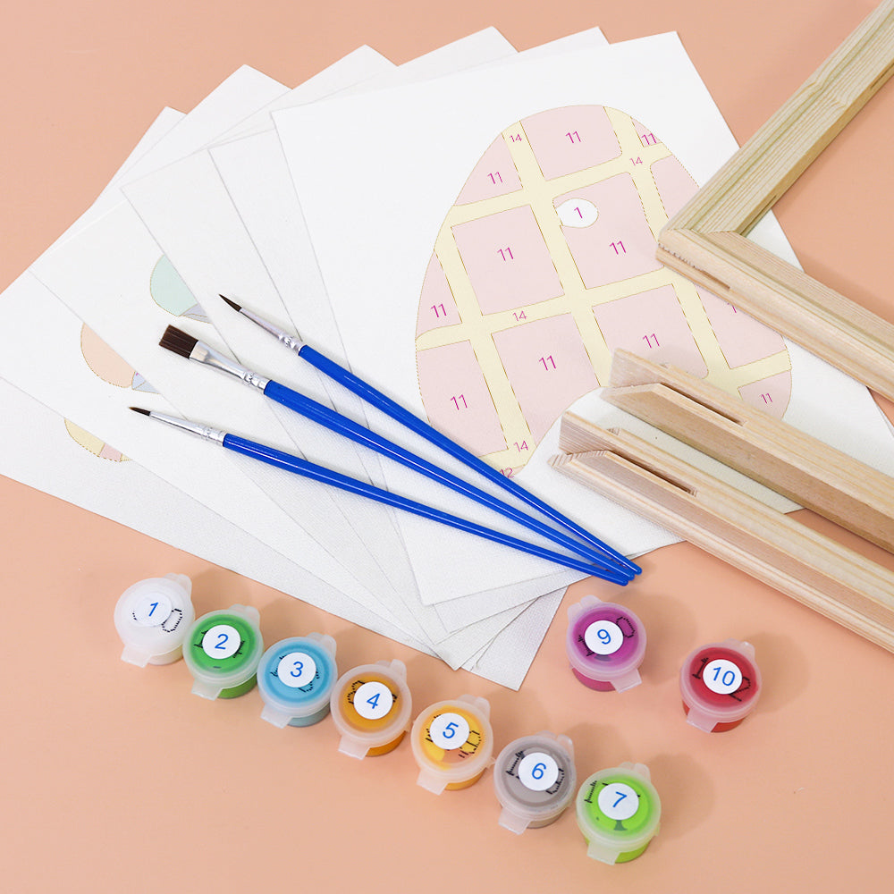 Art supplies including paintbrushes, color swatches, and a small easel on a peach background