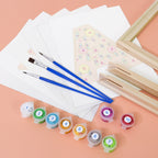 Art supplies including brushes, paint containers, and a wooden frame on a peach background
