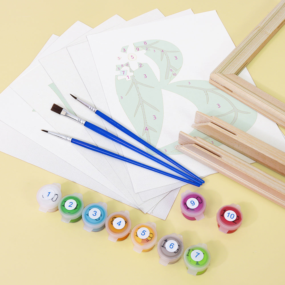 Art supplies including paintbrushes, paint containers, and paper with leaf drawings on a yellow background
