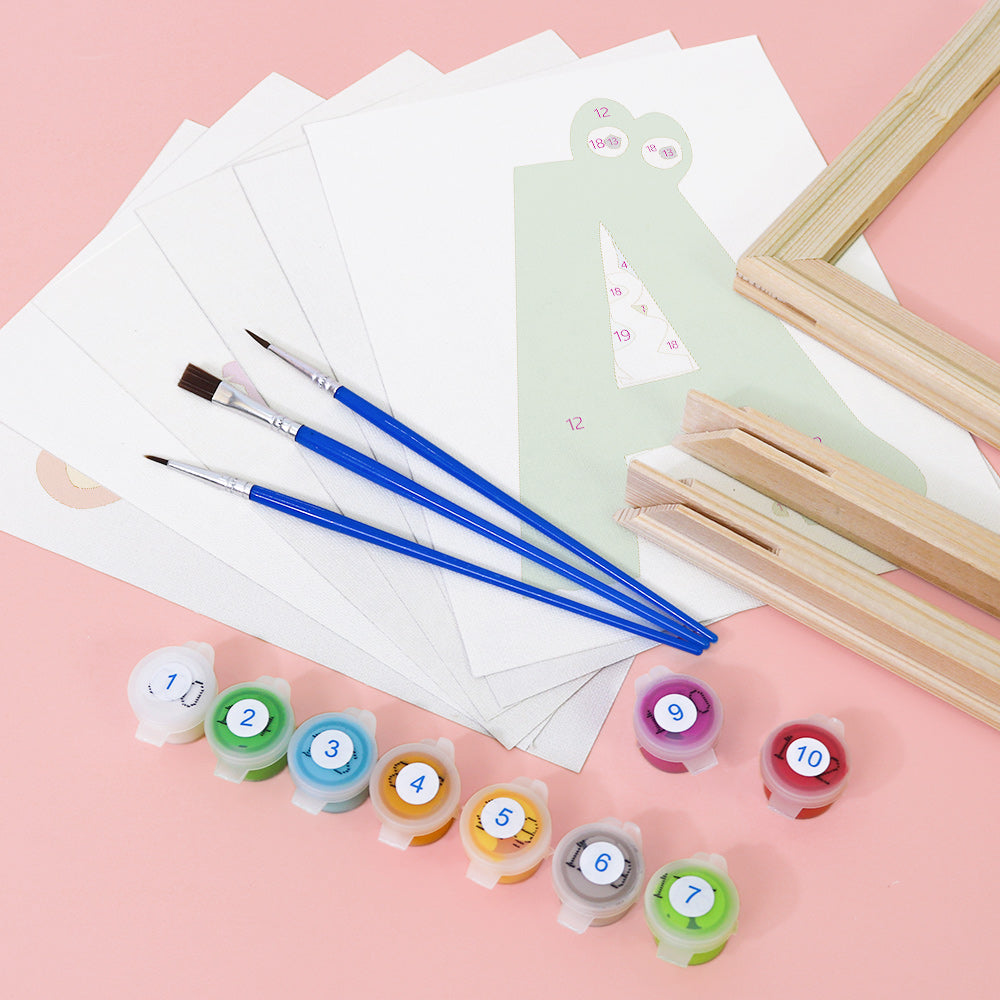 Art supplies including paintbrushes, paint containers, and canvases on a pink background