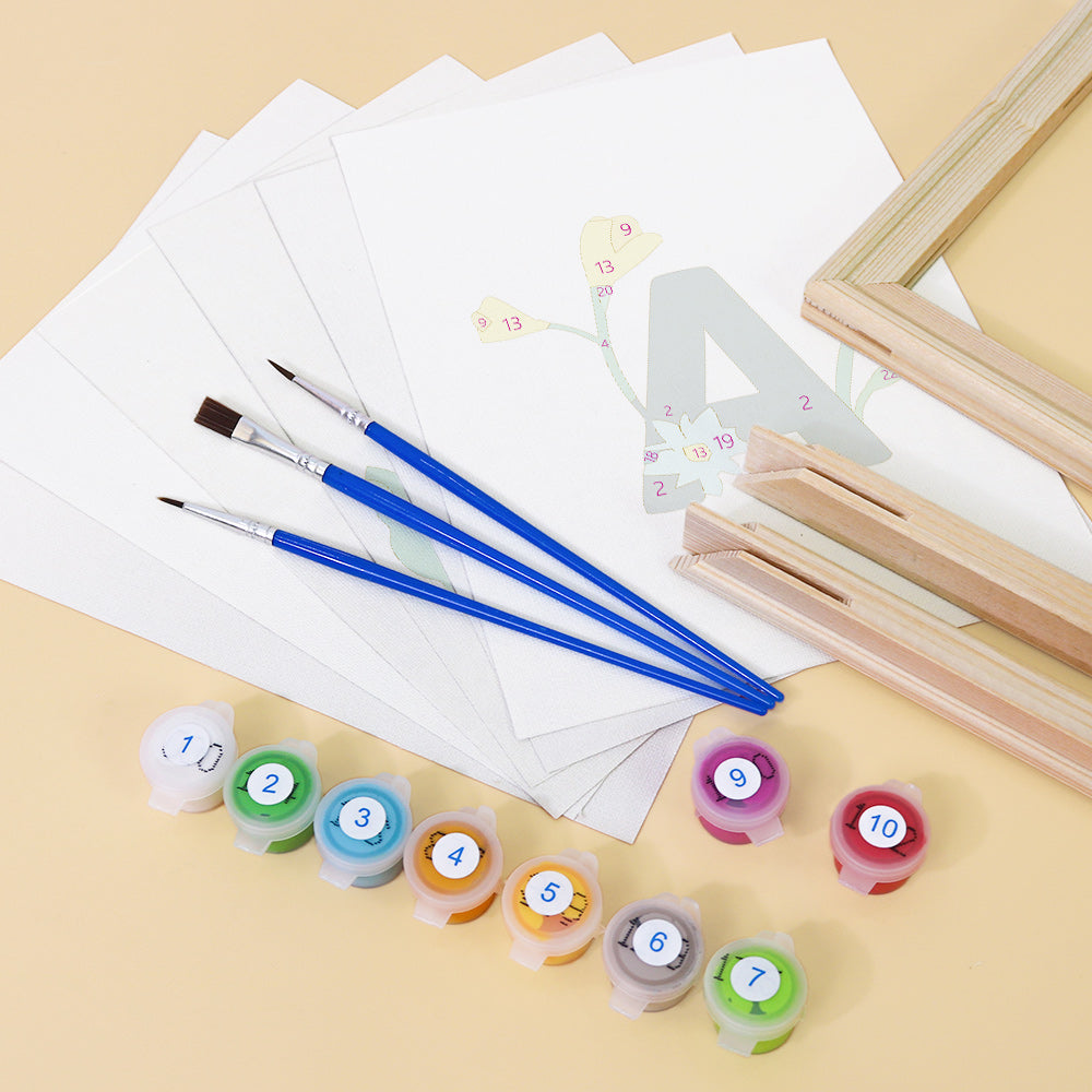 Art supplies including paintbrushes, paint containers, and a wooden frame on a beige surface.