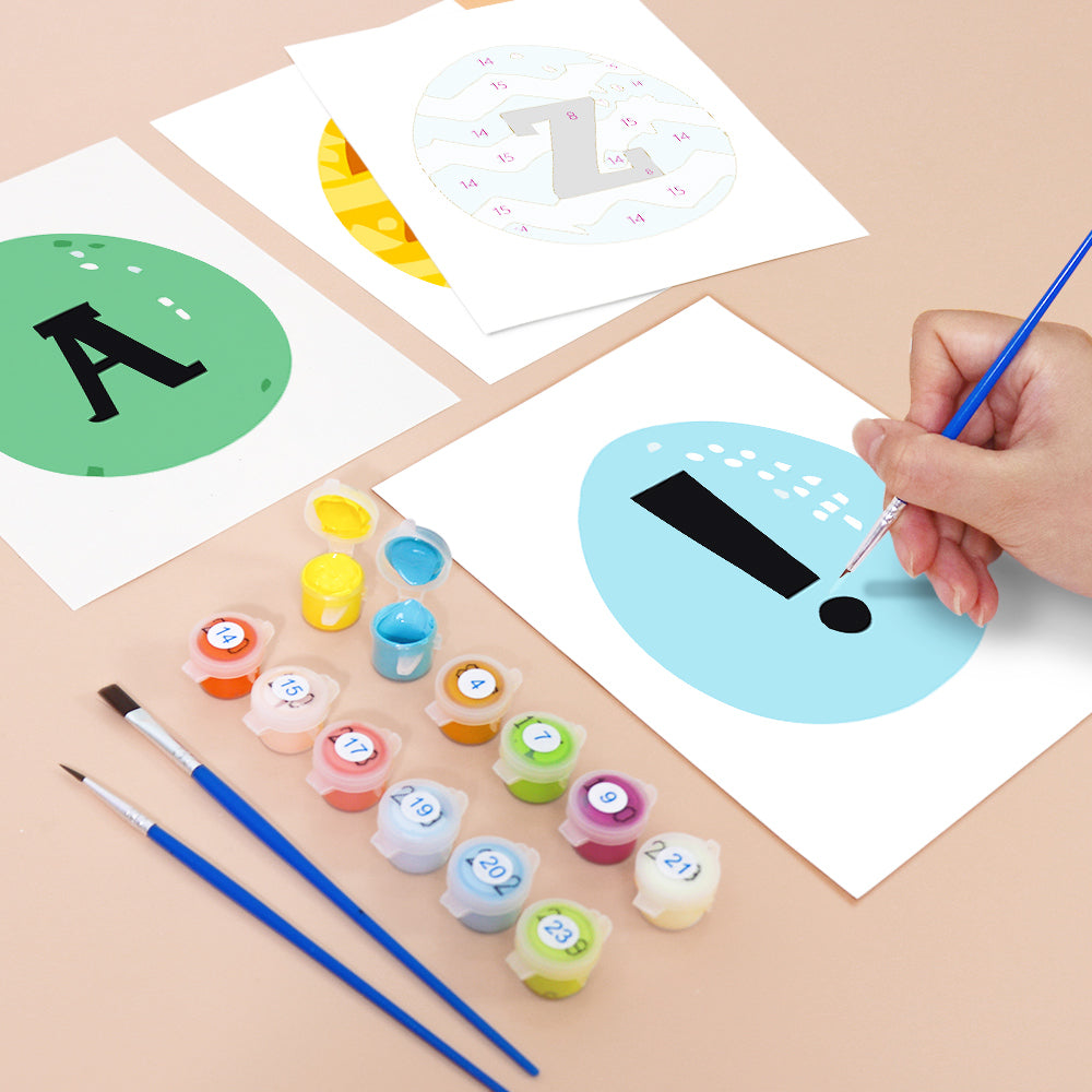 Children's art project with letters and numbers on paper, paint containers, and brushes.