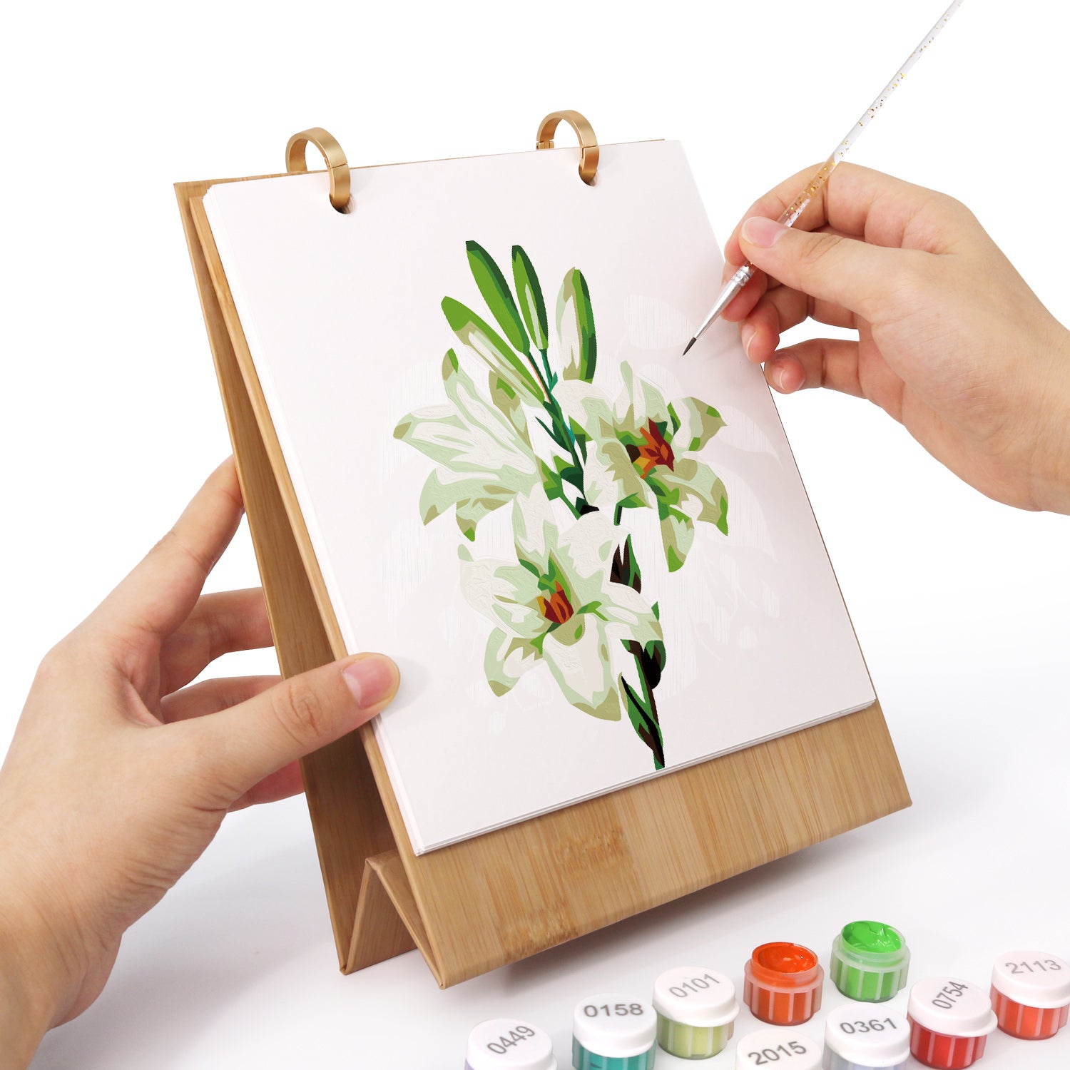 Person painting a floral scene on a small easel with watercolor paints.
