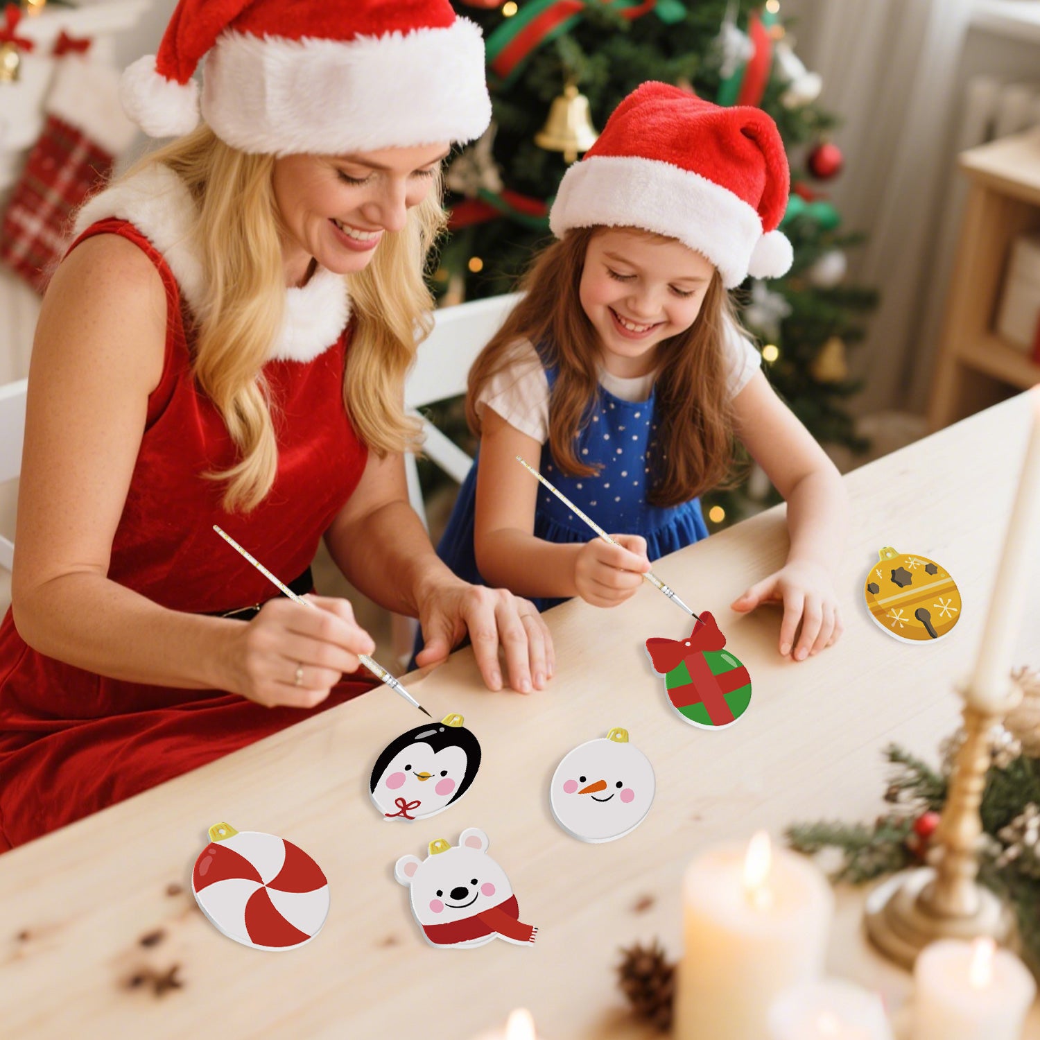 Woman and young girl wearing Santa hats decorating Christmas ornaments with a decorated tree in the background.