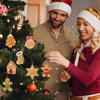 Man and woman in festive attire decorating a Christmas tree with gingerbread-themed ornaments.