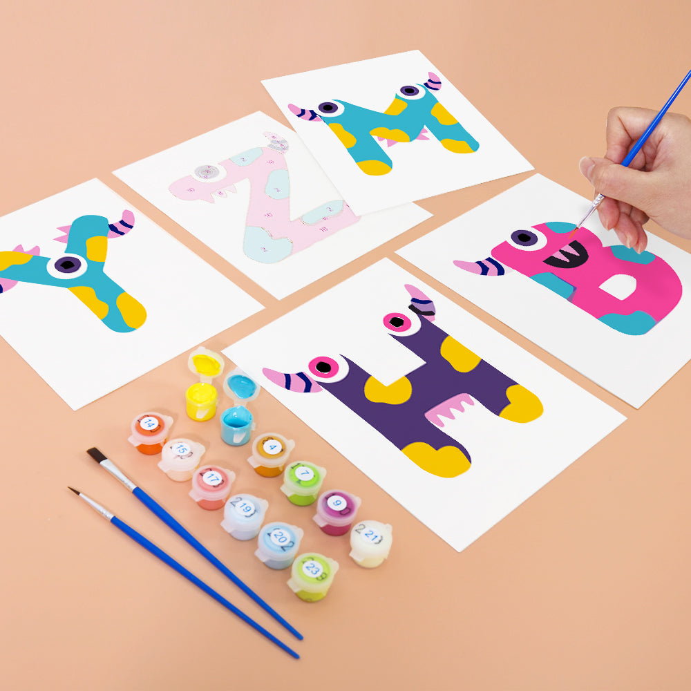 Children's art project with colorful letters on paper and paint supplies.