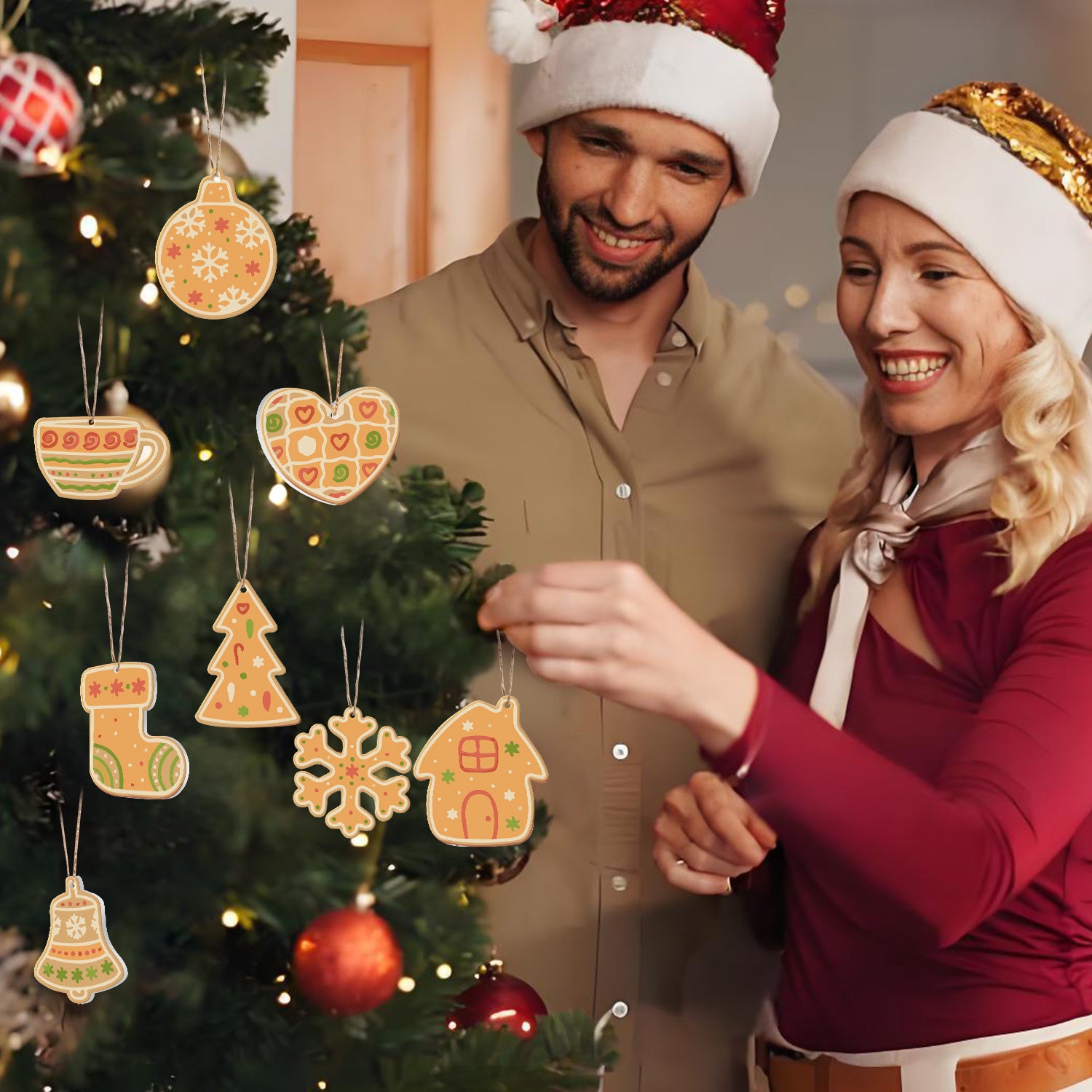 Man and woman in Santa hats standing next to a decorated Christmas tree with gingerbread-themed ornaments.