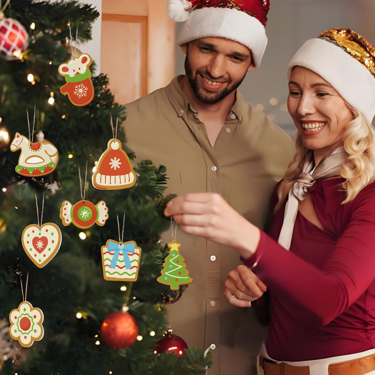 Man and woman in festive attire decorating a Christmas tree with gingerbread-themed ornaments.