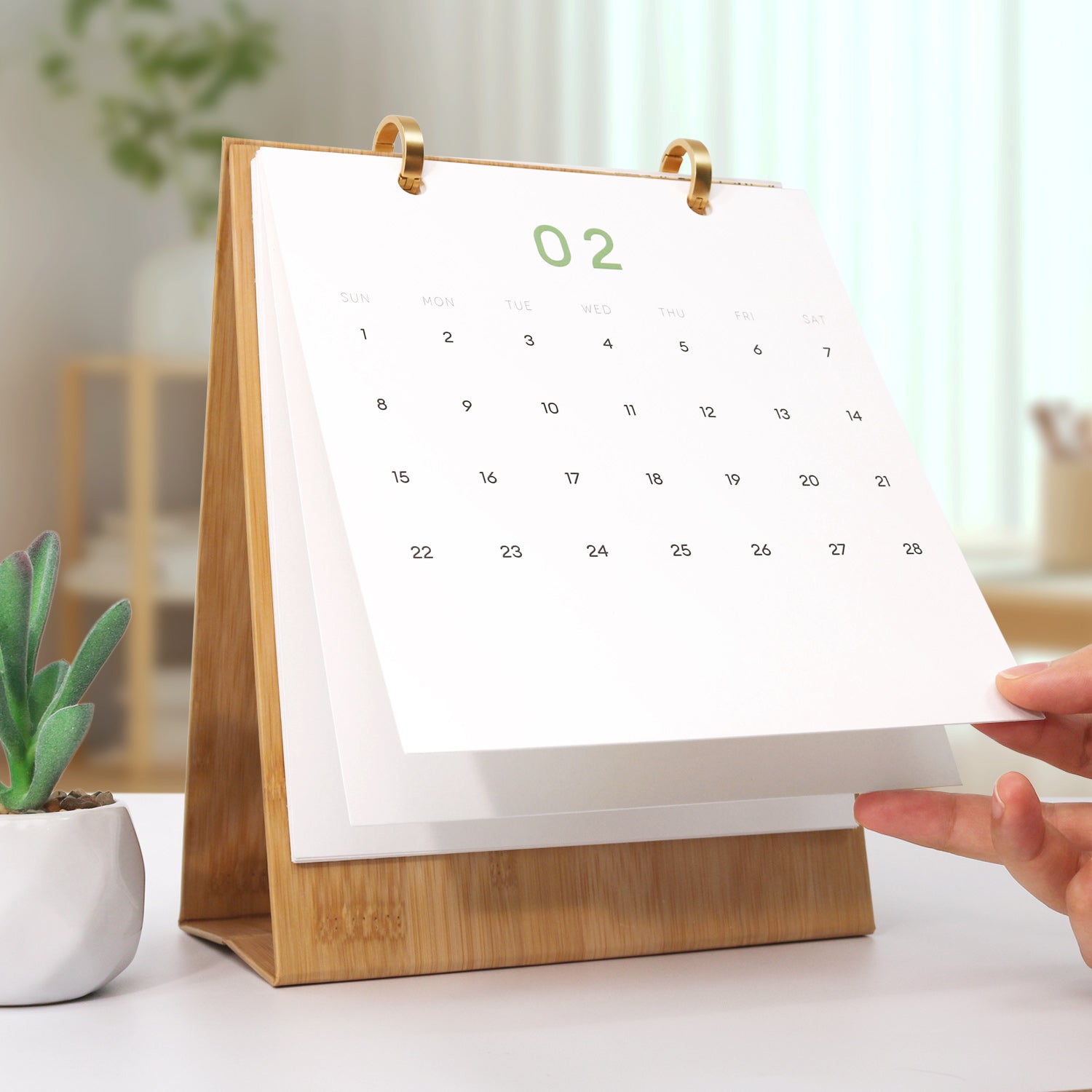 Calendario con soporte de madera sobre una mesa, con una mano ajustando la página.