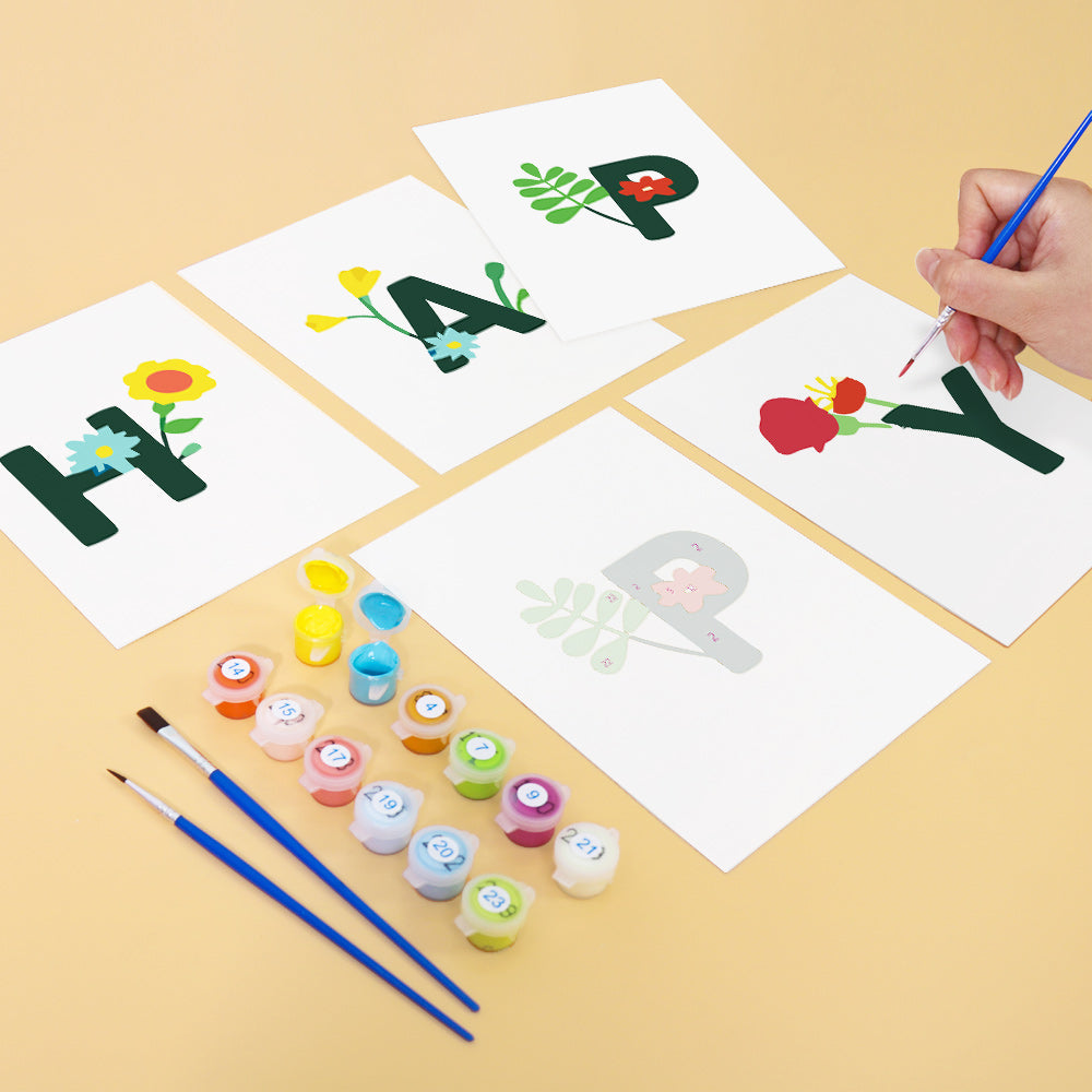 Children's art project with letters 'H', 'A', 'P', and 'Y' being painted on paper with paint supplies.