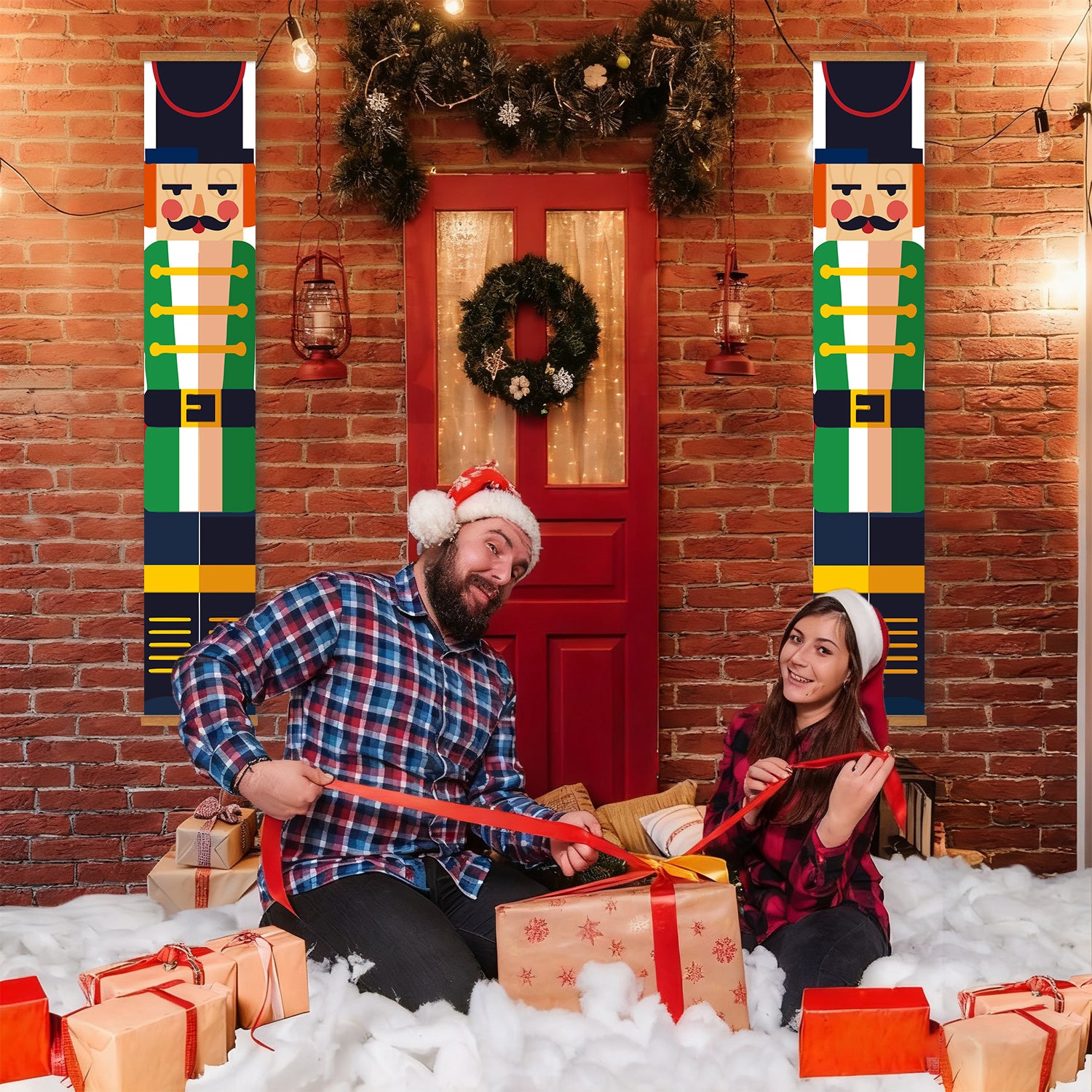 Two people in festive attire sitting on a snowy floor with Christmas decorations and presents.