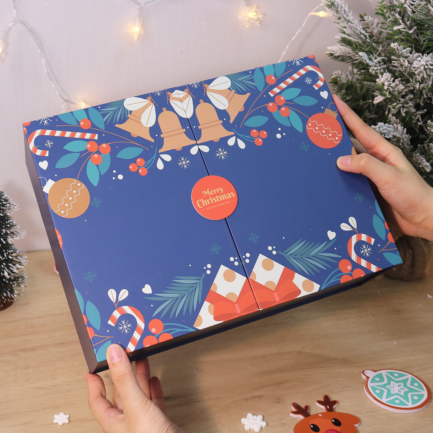 Person holding a Christmas-themed advent calendar with festive designs on a wooden surface.