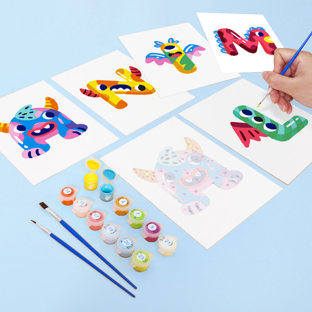 Children's art project with colorful letters and animals on paper, surrounded by paint bottles and brushes.