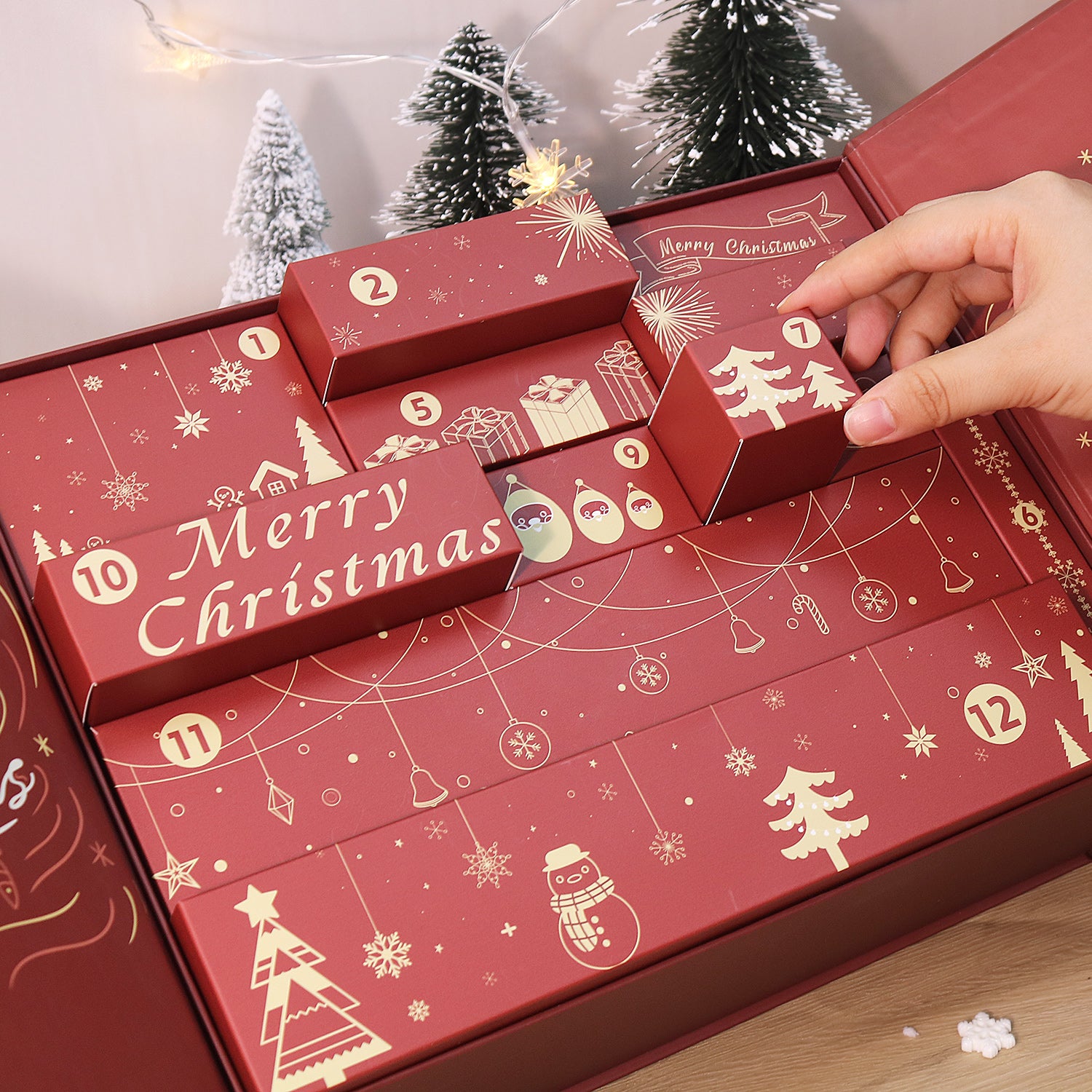 Red Christmas advent calendar with festive designs and a hand opening one of the doors.