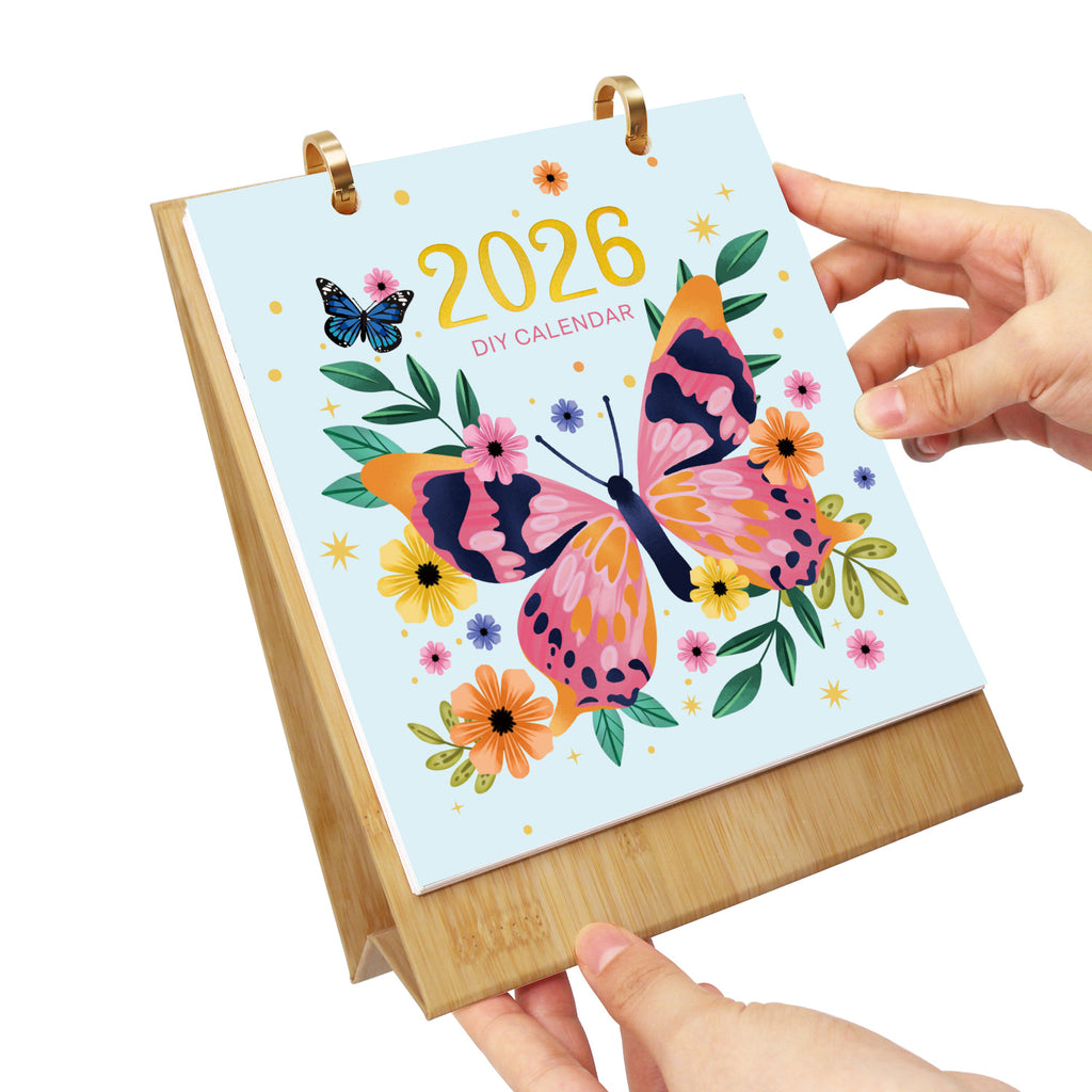 DIY-Kalender 2026 mit Schmetterling und Blumenmuster, gehalten von einer Hand auf weißem Hintergrund