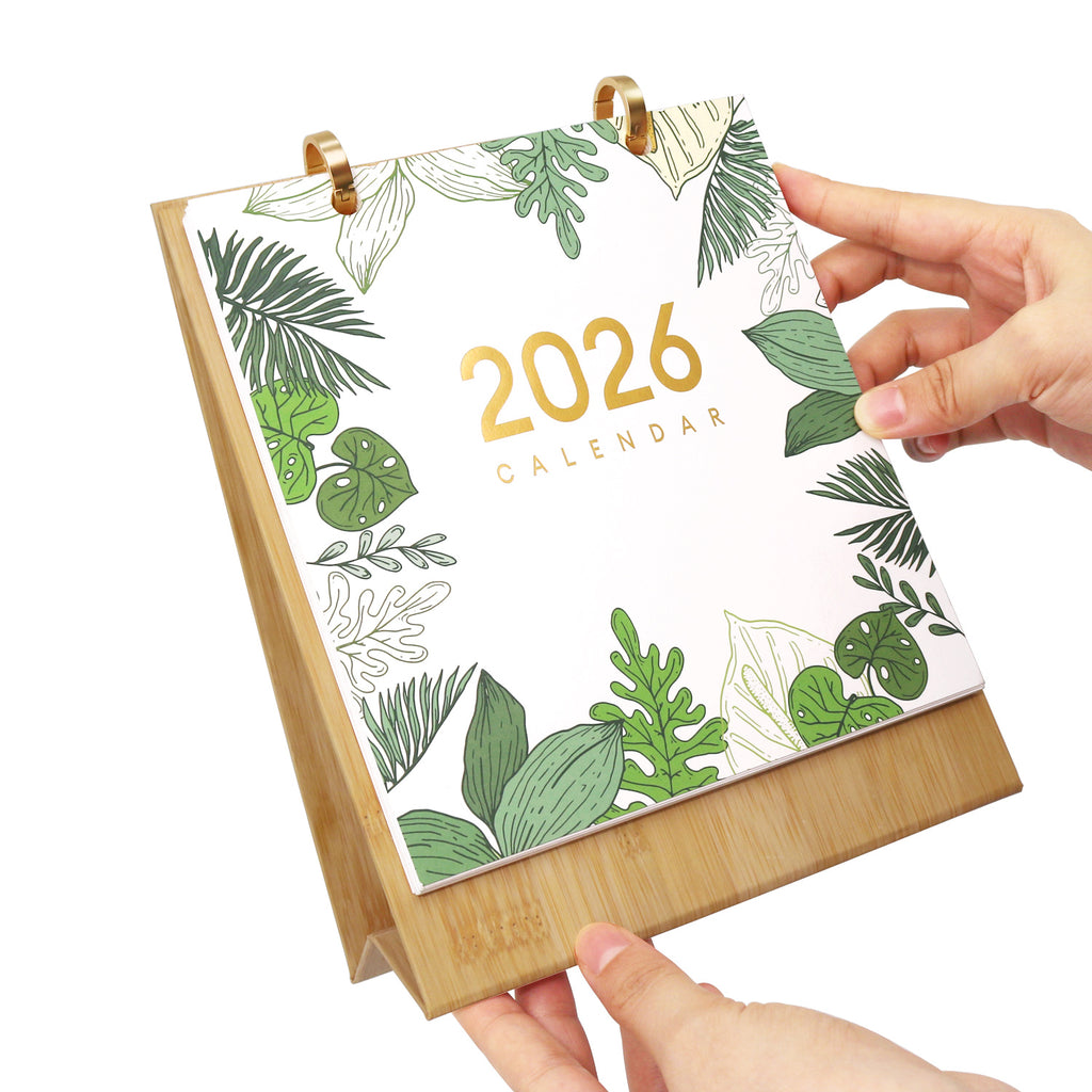 2026 calendar with leaf design held by a hand on a white background