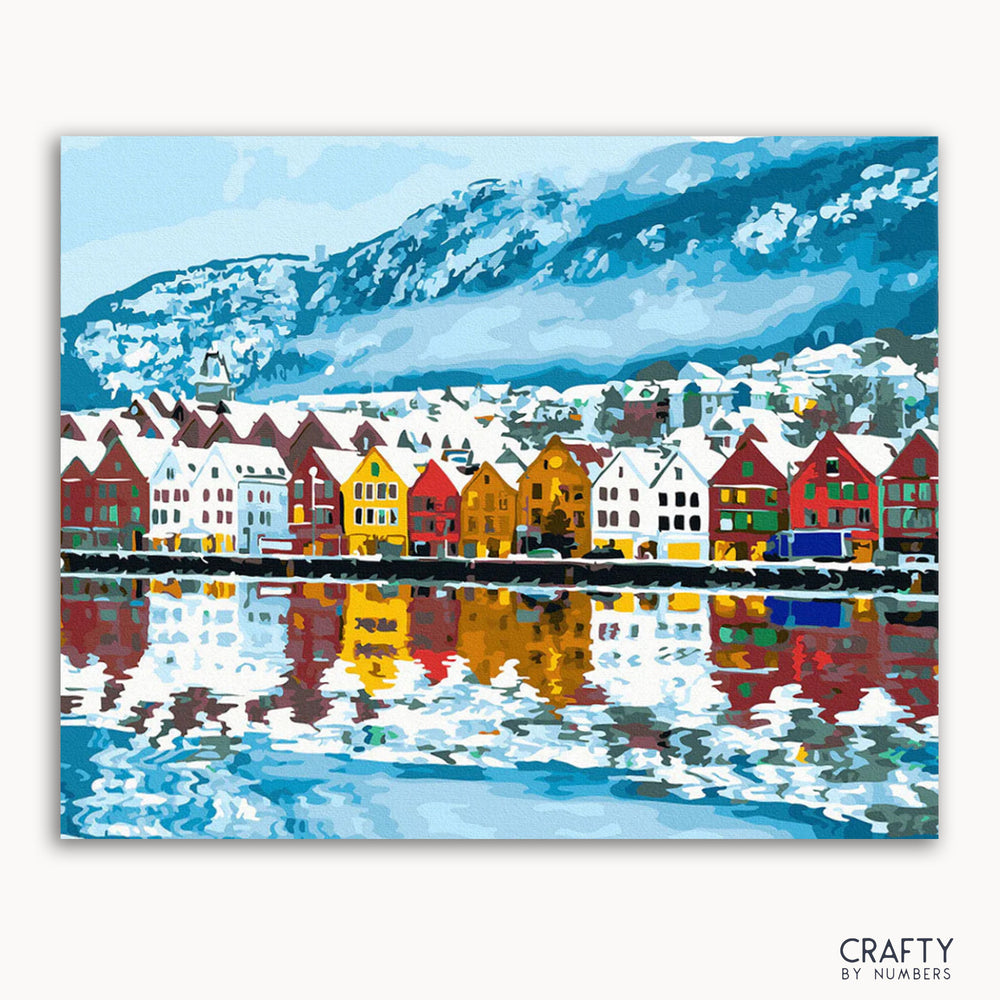 A painting of a vibrant cityscape with colorful buildings lining a waterfront, with mountains in the background.