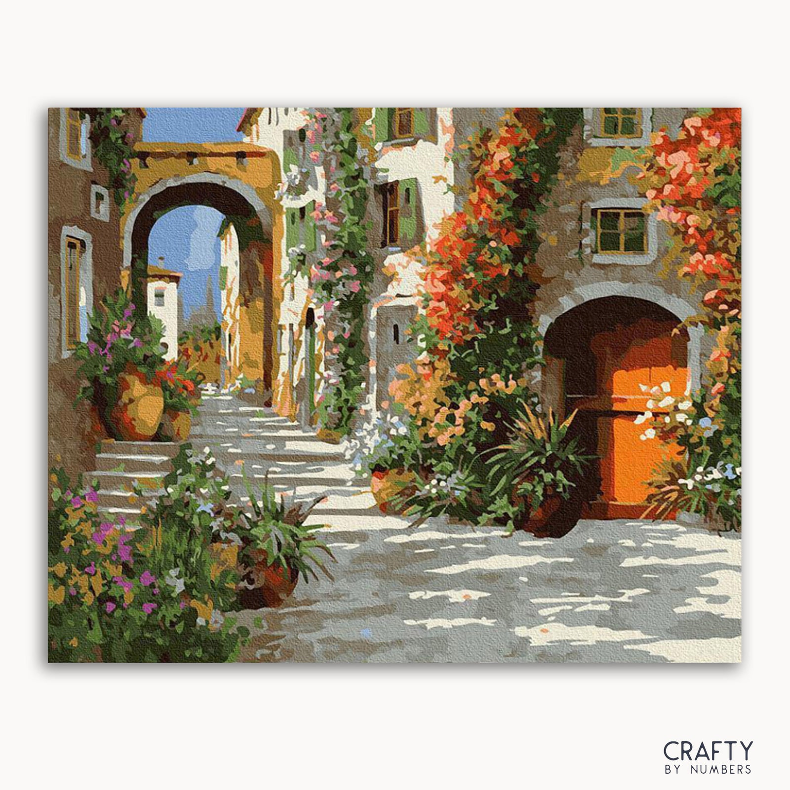 Ein lebendiges Gemälde mit dem Titel „The Yard in Flowers“ von Crafty by Numbers, das eine schmale Straße mit bunten Blumen und alten Gebäuden zeigt.