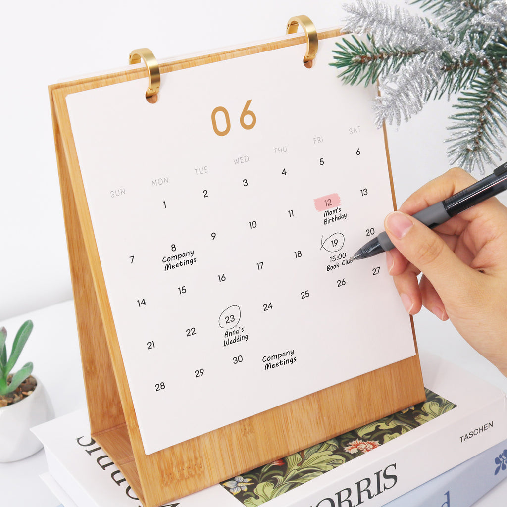 Calendario con una mano marcando fechas, rodeado de adornos navideños.