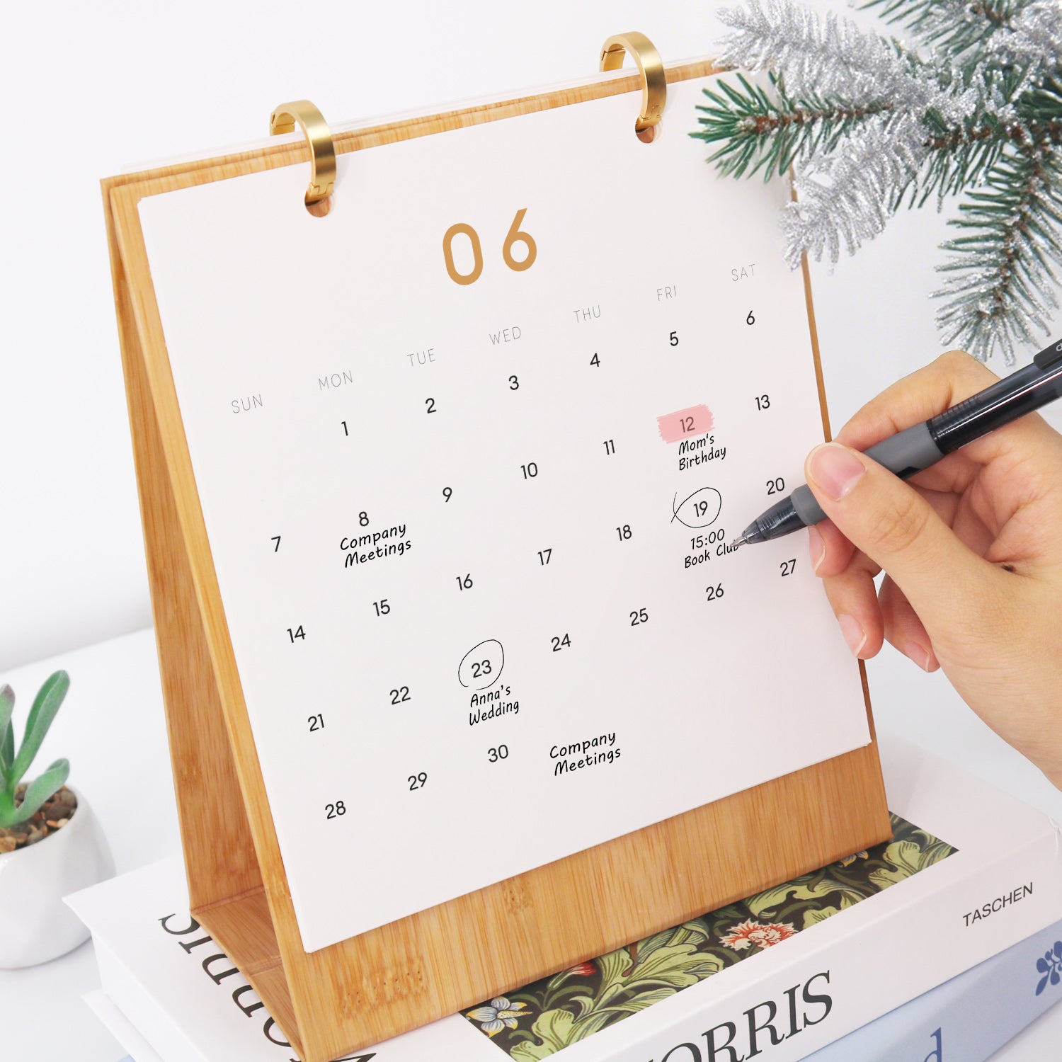 Calendario con una mano marcando fechas, rodeado de adornos navideños.
