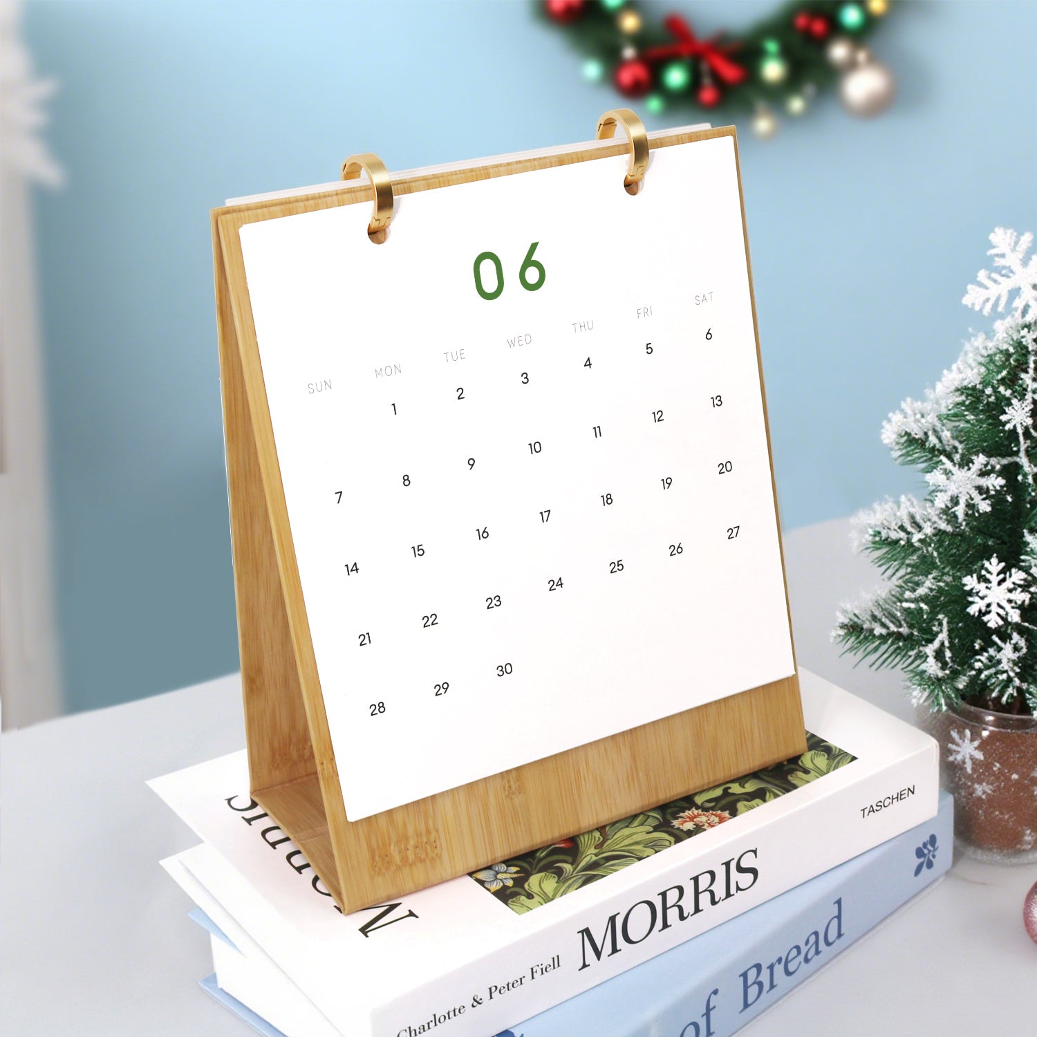 Calendario sobre una pila de libros con una corona navideña al fondo