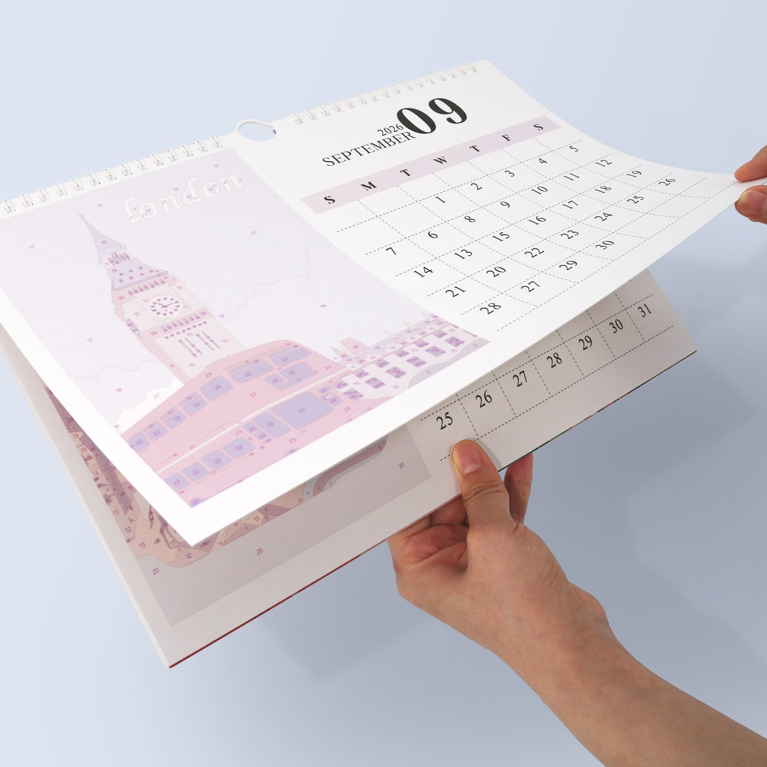 Calendar open to September with a hand holding it, on a light blue background