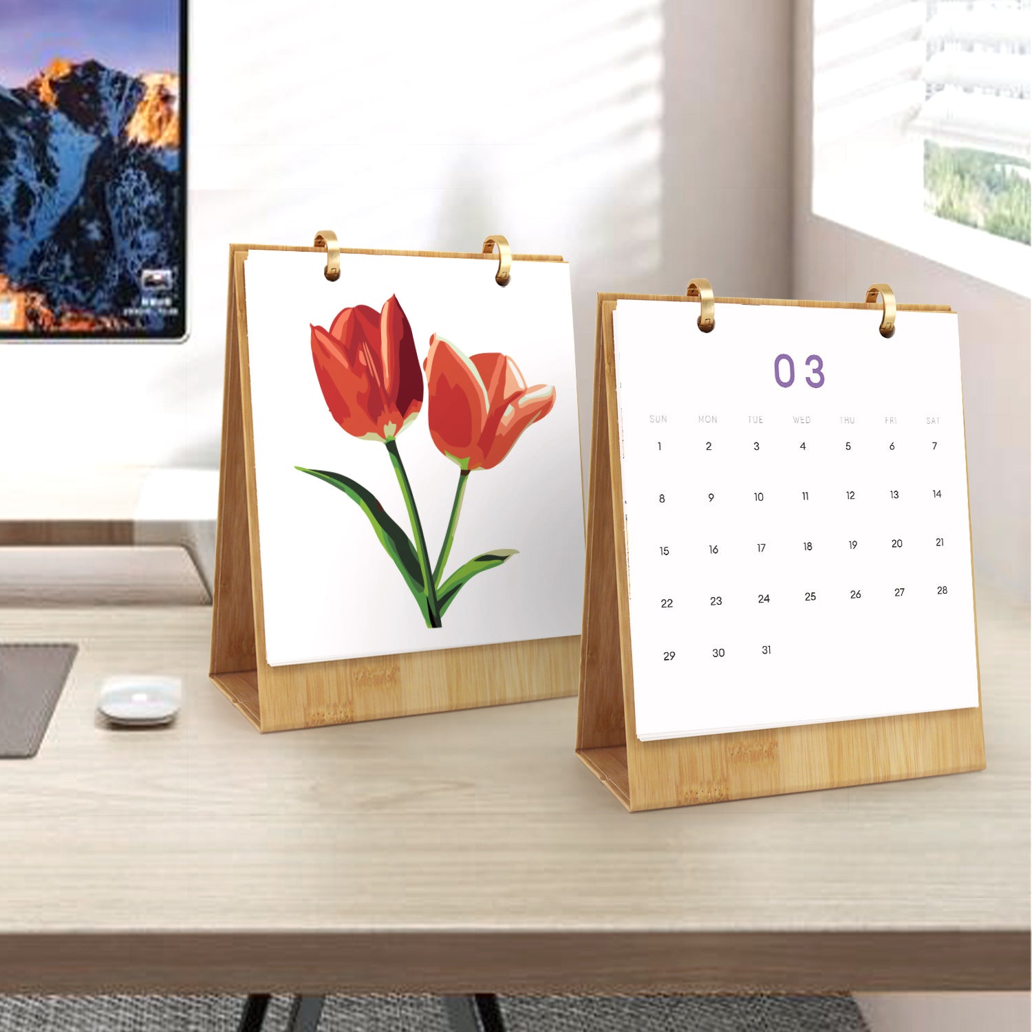 Two desk calendars on a wooden surface with a computer screen in the background.
