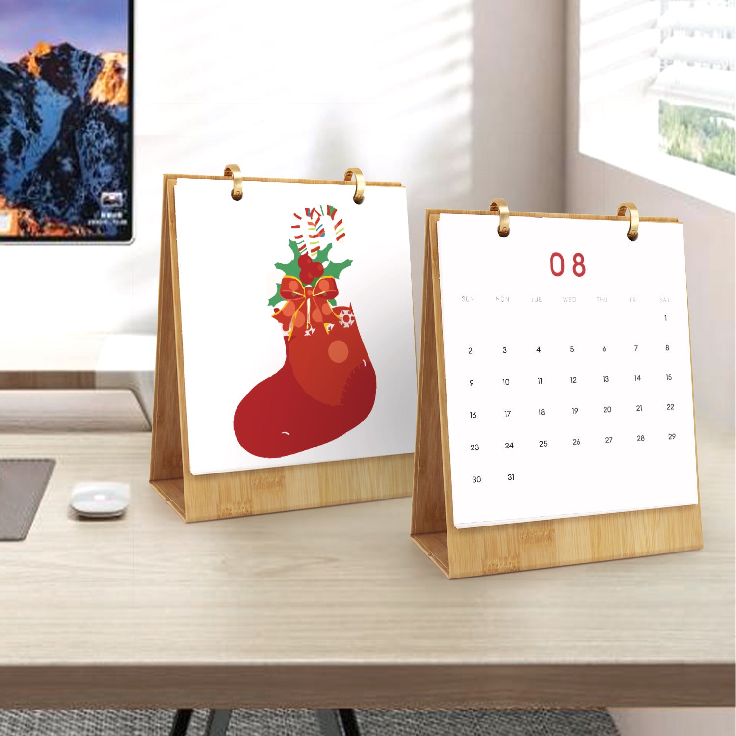Two desk calendars on a wooden surface with a mountain view in the background