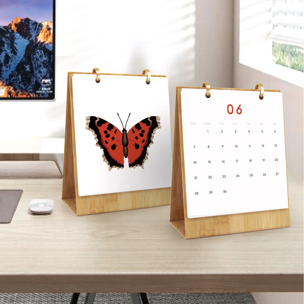 Zwei Tischkalender auf einer Holzoberfläche mit Schmetterlingsdesign und Kalendernummern.