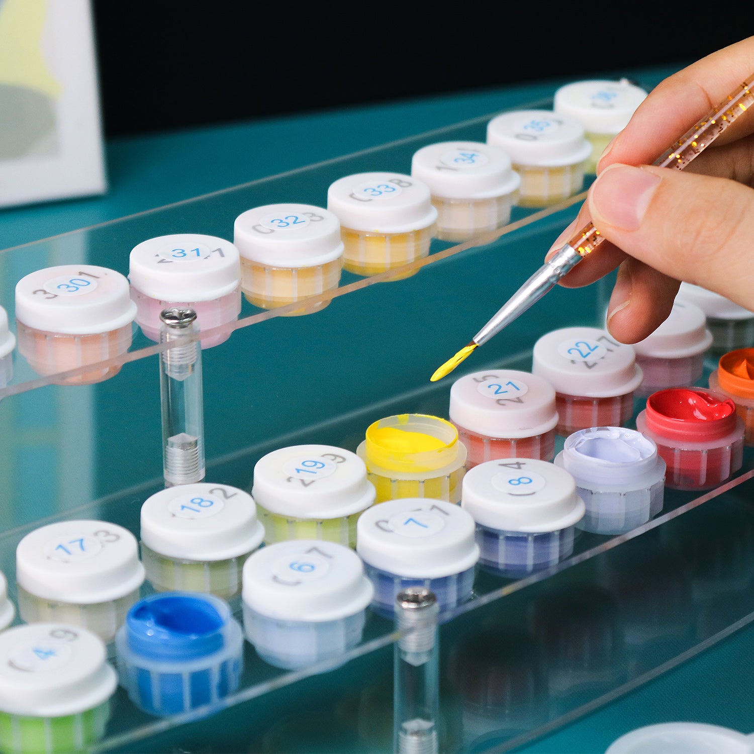 Person using a pipette to transfer liquid into small containers labeled with numbers on a glass surface.