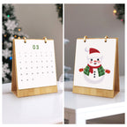 Small calendar with a wooden stand, showing the number 03, and a snowman illustration on a white surface.