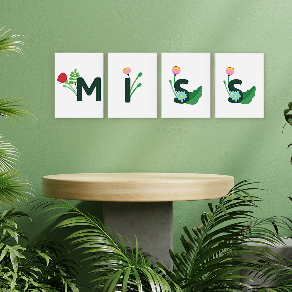 Vier gerahmte Kunstwerke mit der Aufschrift „MIS“ an einer grünen Wand mit einem Holztisch und Pflanzen.