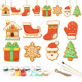 Set of Christmas-themed cookie cutters with paint supplies on a white background