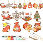 Set of Christmas-themed ceramic decorations with painting supplies on a white background