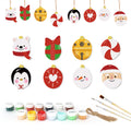 Set of Christmas-themed ceramic ornaments with painting supplies on a white background