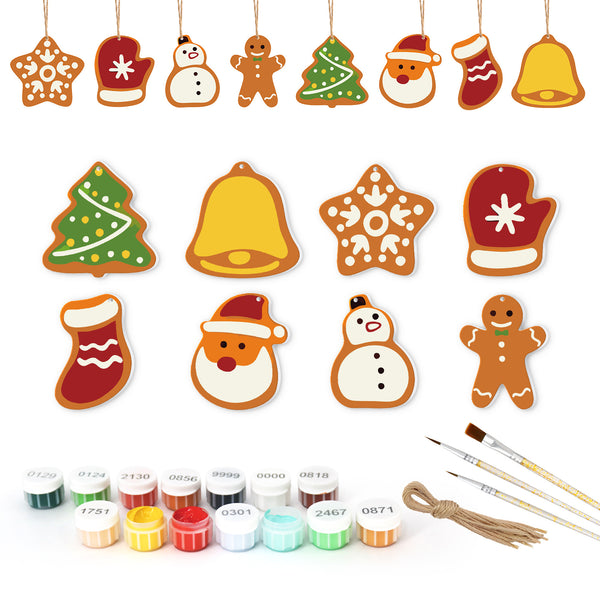 Set of Christmas-themed ceramic decorations with painting supplies on a white background