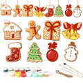 Set of Christmas-themed ceramic decorations with painting supplies on a white background