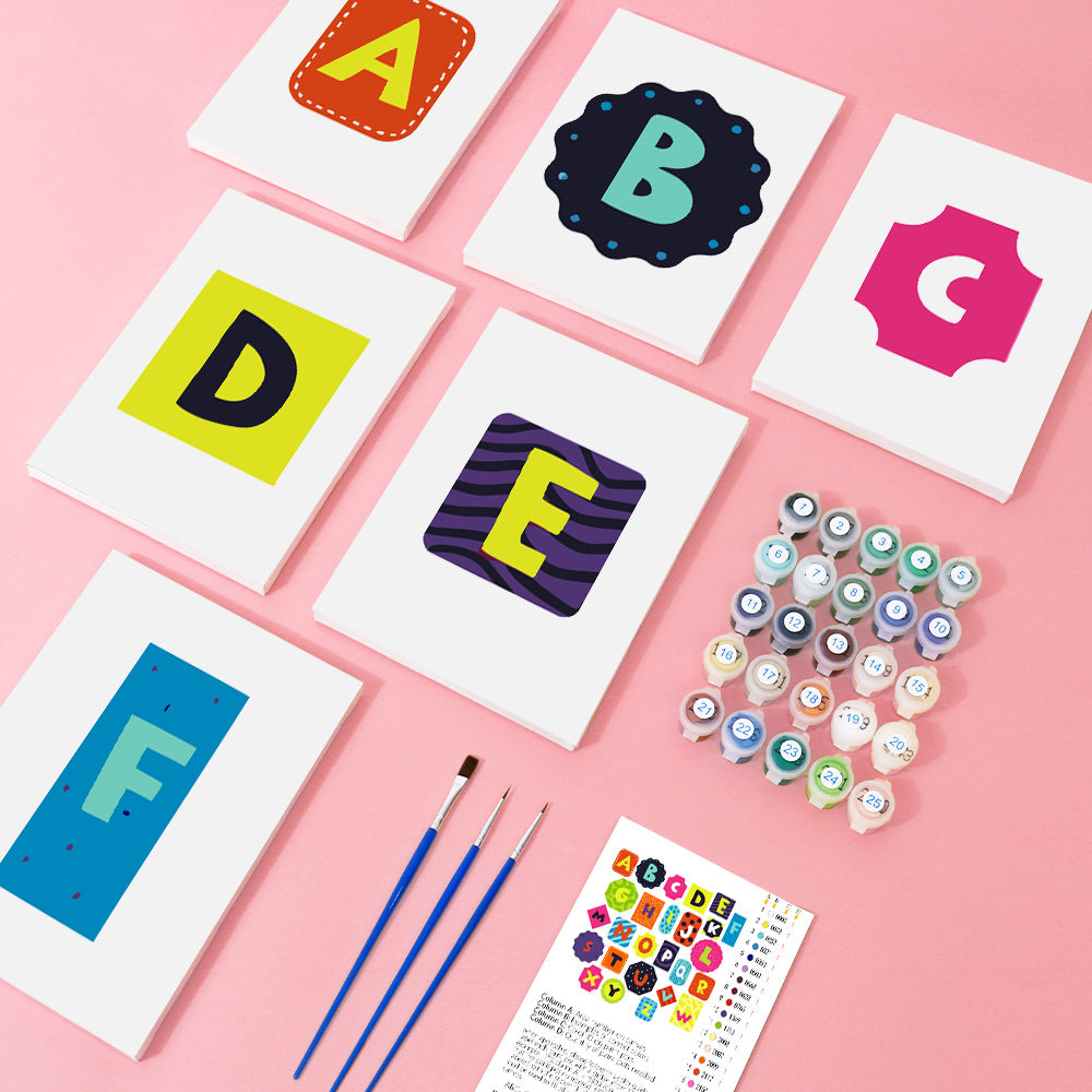 Colorful alphabet cards with paint bottles and brushes on a pink background