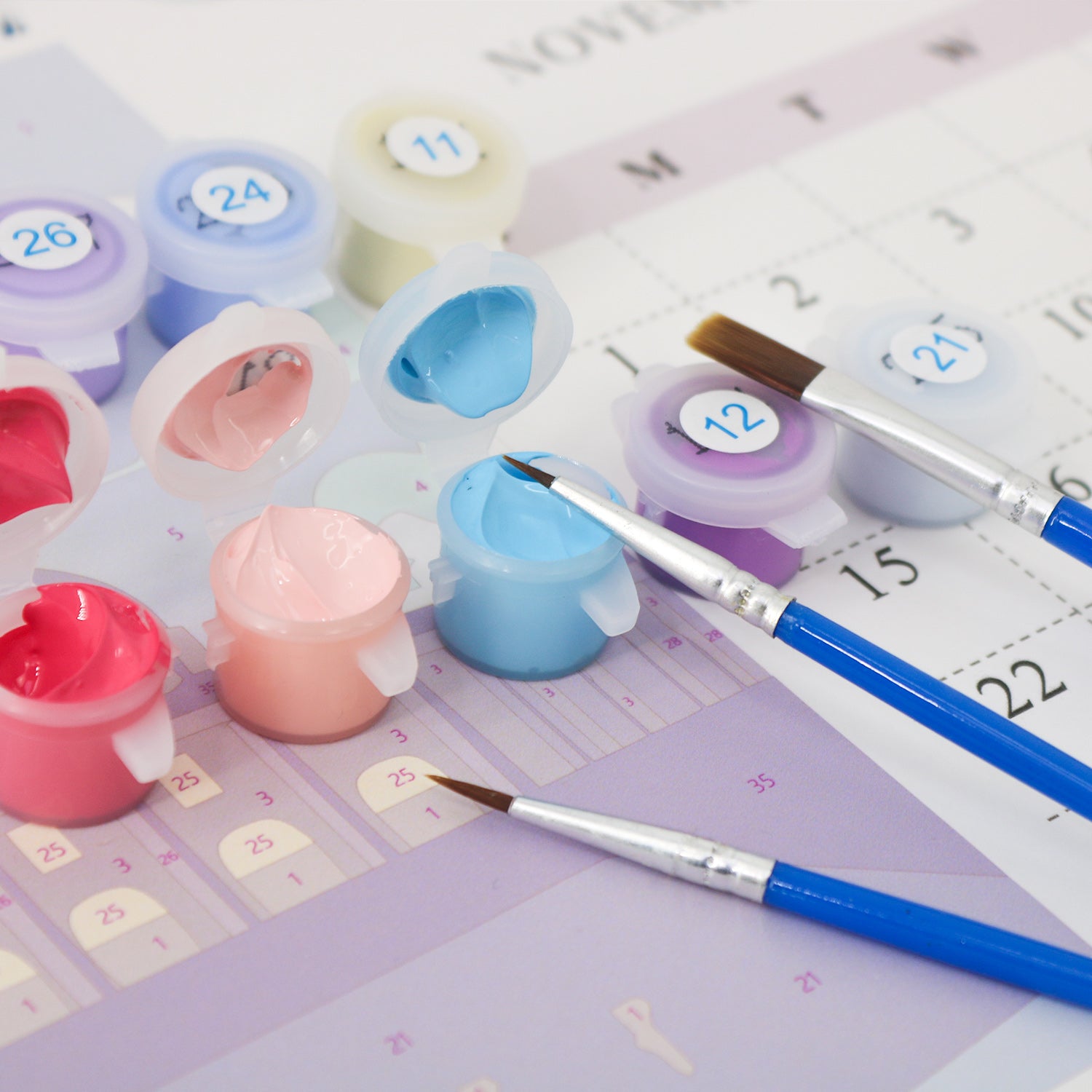 Set of colorful paint pots and brushes on a calendar background
