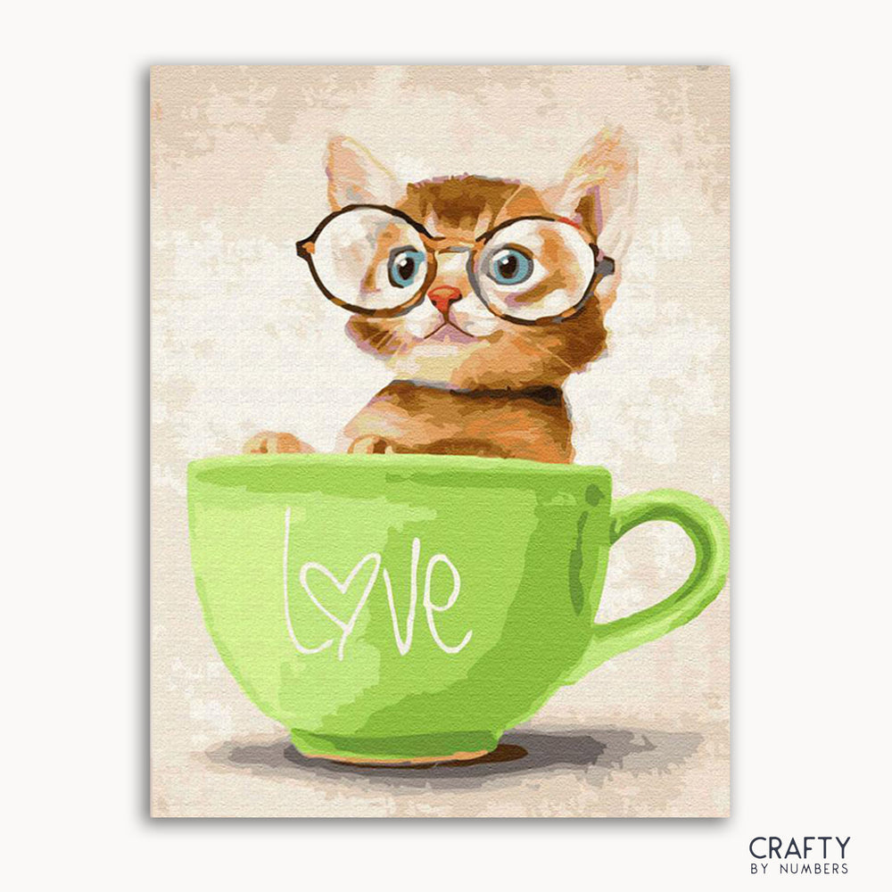 A pop-up art kit featuring a cartoon image of a kitten with glasses sitting inside a green cup with the word 'love' on it.